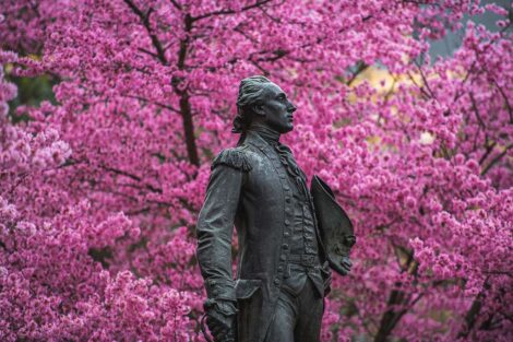 A statue of the Marquis de Lafayette, in front of Colton Chapel and pink trees.
