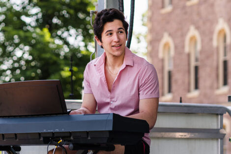 student plays keyboard on a stage on the Quad