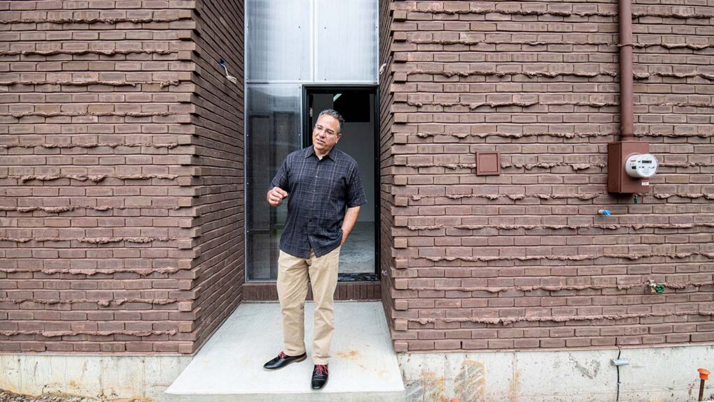 Joe Biondo stands at back entrance with brown bricks on either side of him