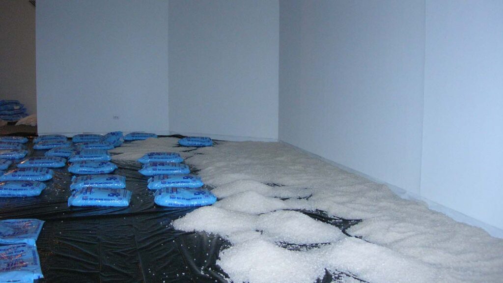 Bags of salt line the floor of the gallery, some bags have already been dumped in piles