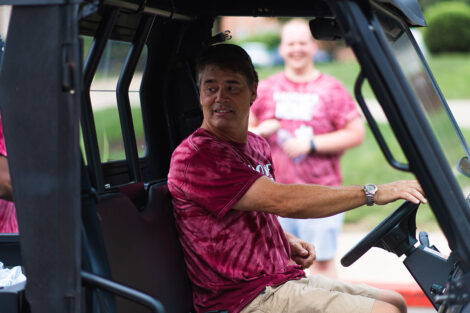Bill Hurd drives a golf cart during move-in weekend, wearing Welcome Home T-shirt