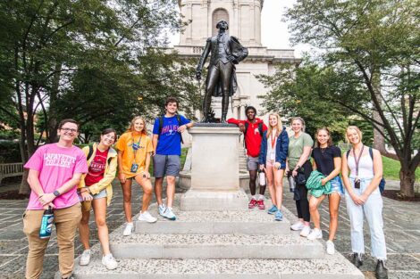 group of students flank the Marquis de Lafayette statue behind Colton Chapel and smile