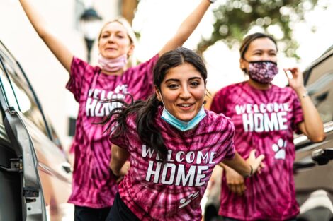 group of students in Welcome home tie-dye shirts smile outdoors