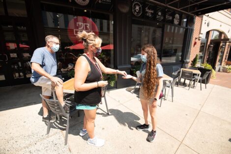 A student exchanges an item with two community members in downtown Easton.