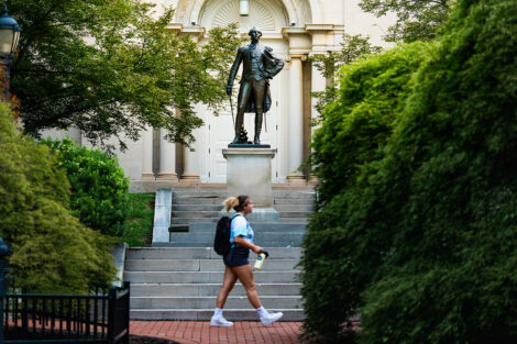A student walks past a statue of Marquis de Lafayette, behind Colton Chapel.