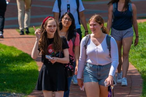 A group of students walk, engaged in conversation, along the brick pathway of Lafayette College.