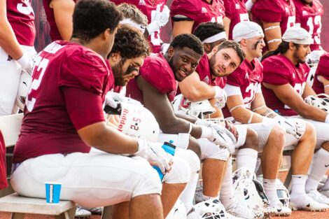 Football players talk on the sidelines of Fisher Field.