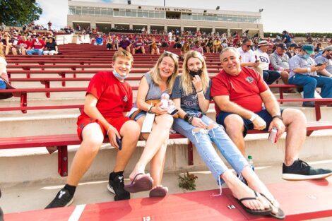 A family watches the football game from the stands of Fisher Stadium.