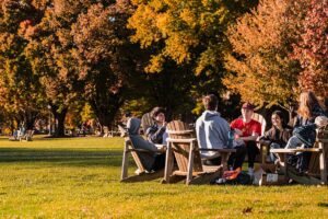 group of students sit on the Quad in Adirondack chairs