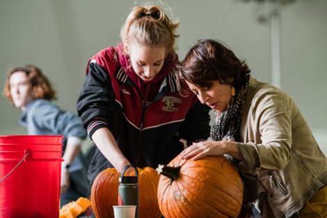 Prof. Megan Rothenberger and a student carve pumpkins