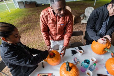 students gather around pumpkins on table