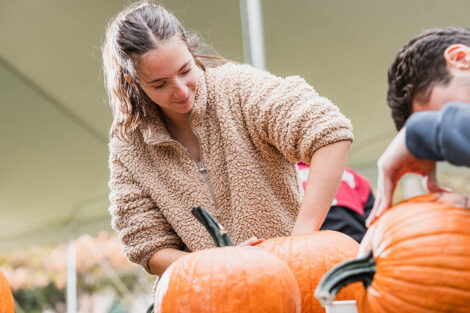 student digs hand into the top of a pumpkin