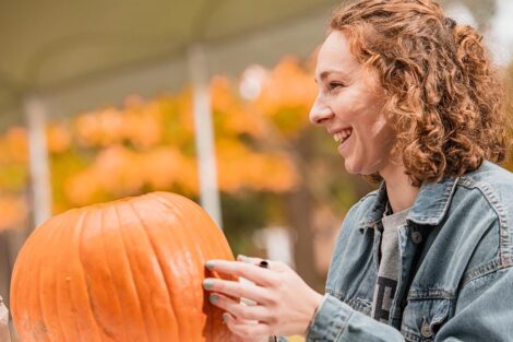 student smiles under tent on Quad with pumpkin