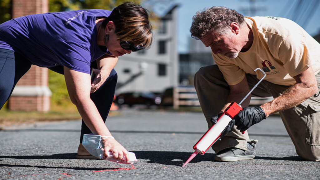 Maria Ragonese (left) of PAZA, Tree of Life, and Jim Toia, executive director of the Karl Stirner Arts Trail and director of Lafayette’s community arts program fill cracks with red sand 