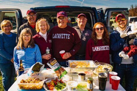 group of alumni in Lafayette gear with a spread of food near open car trunk