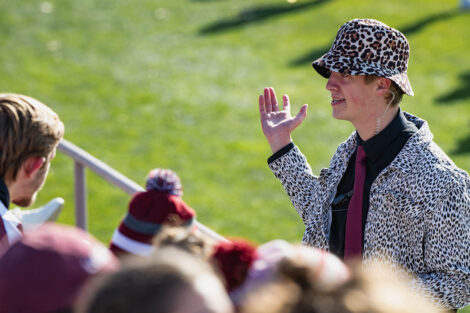 band director in leopard-print hat and jacket directs the band in the stands