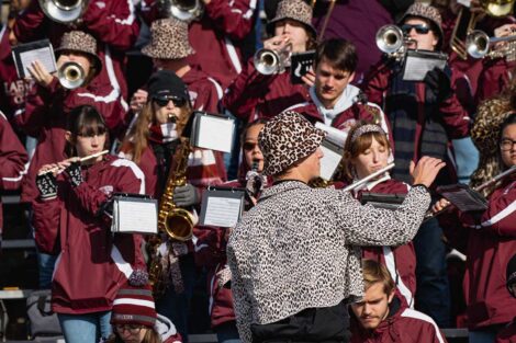band director in leopard-print hat and jacket directs the band in the stands
