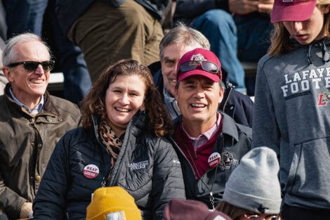 President Nicole Farmer Hurd and husband Bill sit in the stands and smile