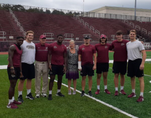 Allen and Janet Haddad pose at Fisher Field with the current members of the football team who they sponsor 