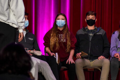 Students, wearing masks listen to hypnotist Erick Kand.