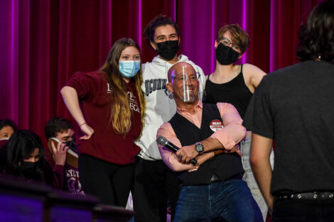 Students, wearing masks, pose with hypnotist Erick Kand.