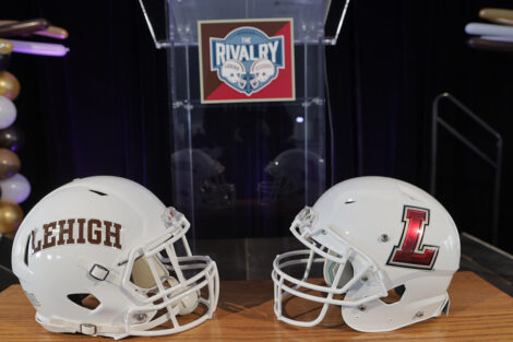Lehigh and Lafayette football helmets on a table, Rivalry sign on podium behind