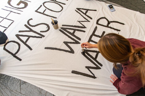 A student paints a banner that reads 
