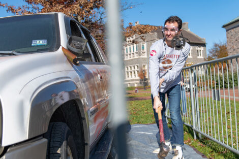 A student hits an SUV with a sledgehammer.