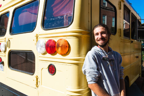 Remy Oktay '23 stands in front of the bus he converted into a solar home