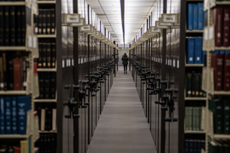 bookcases of books in Skillman library frame a student in the distance