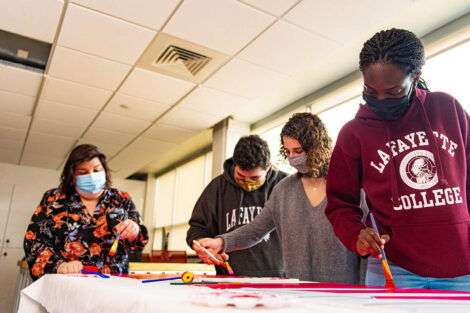 Lisa Karam and engineering students paint a sign in Acopian