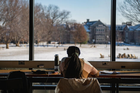 A student looks out a window at Skillman Library