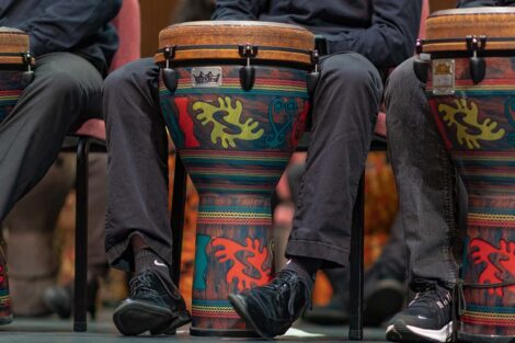 a painted drum sits between a performer's legs