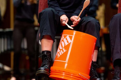 students hit Home Depot buckets with wooden spoons