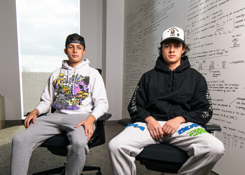 Identical twin Lafayette students Dylan and Adam Fletcher sitting next to each other in a classroom in front of a white board