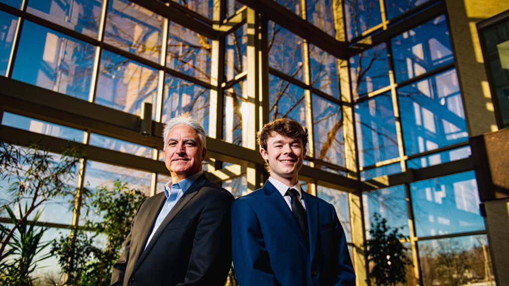 Host and student are in suits in window foyer