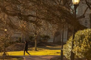 student walks on campus with warm spring sun setting
