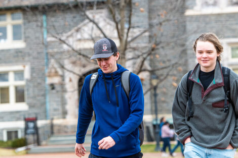 two students walk across the Quad, Hogg Hall in background