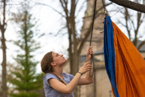 student hangs a hammock in a tree