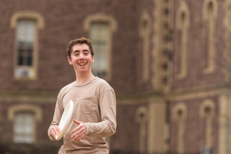 student smiles while holding a frisbee