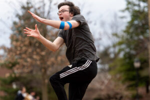 student jumps in the air to catch a frisbee