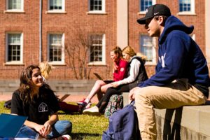 students sitting and talking in the warm sunshine in Anderson Courtyard