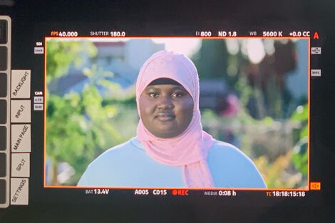 a video camera screen shows Fatimata Cham wears a pink head scarf