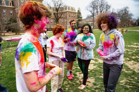 Students toss color powder at each other.