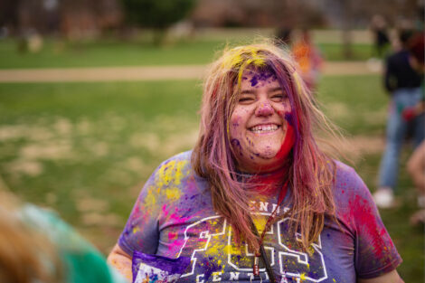 A student smiles, covered in colorful powder.