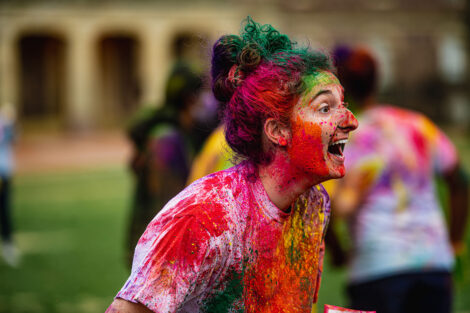 A student covered in many colorful powders.