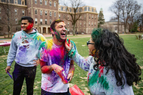 Students toss color powder at each other.