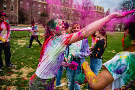 Students toss color powder at each other, in front of Pardee Hall.
