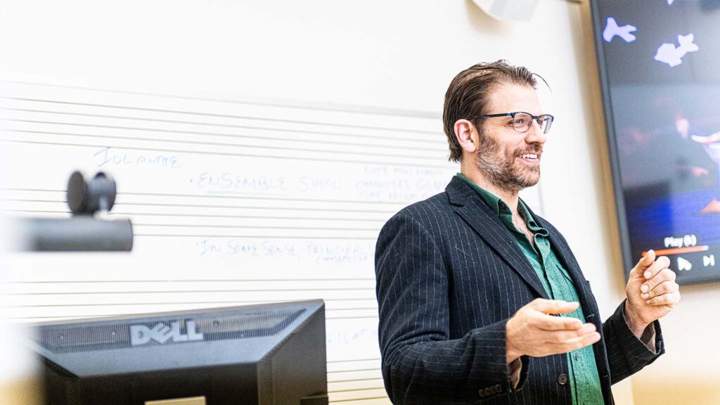 David Wannen smiles at front of classroom while discussing opera