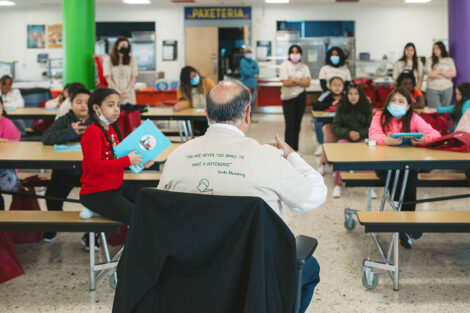 Sal Panto sits and reads a book to elementary school students